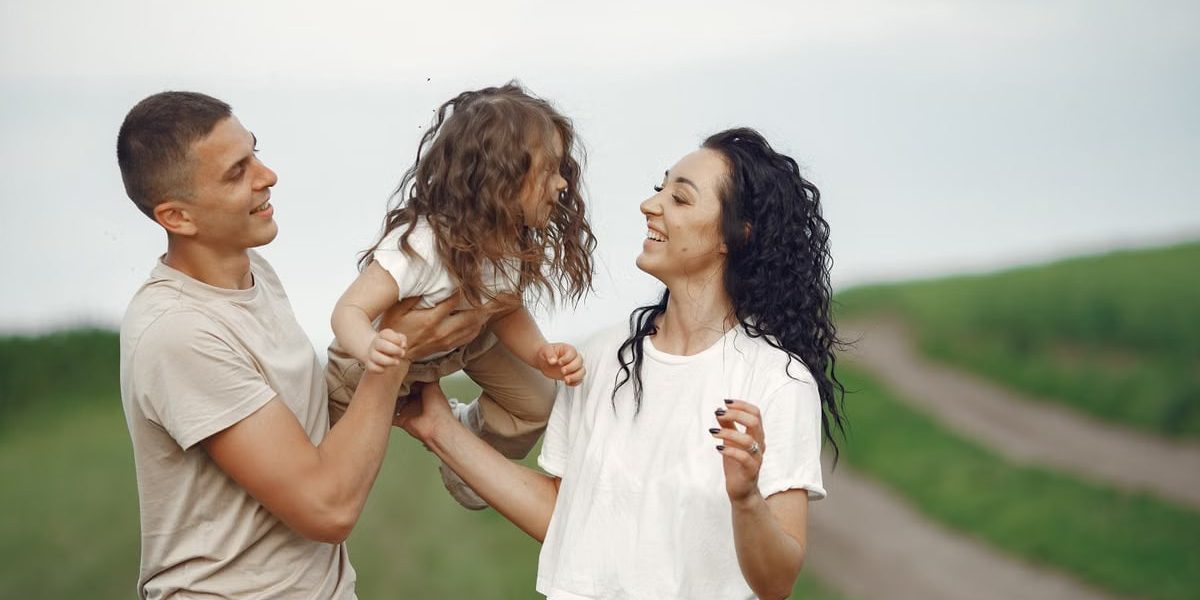 A joyful family moment outdoors with parents playing with their daughter.