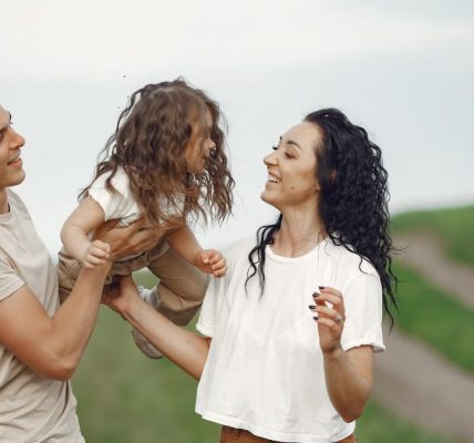 A joyful family moment outdoors with parents playing with their daughter.