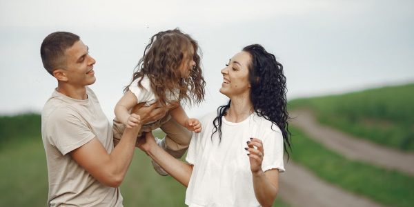 A joyful family moment outdoors with parents playing with their daughter.